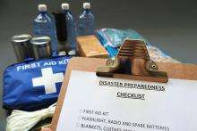 Disaster preparedness checklist on a clipboard with disaster relief items in the background