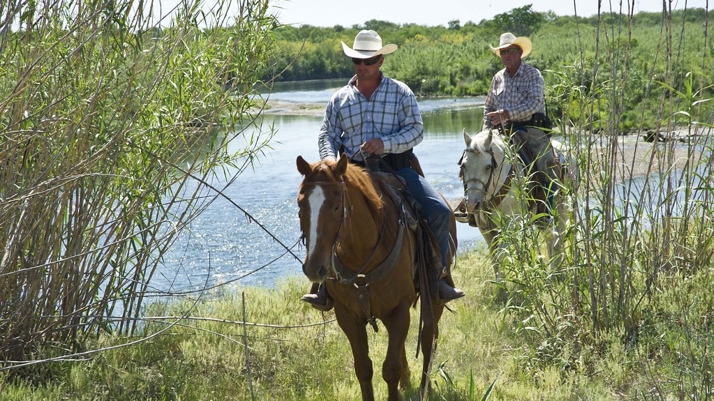 Two APHIS employees on horses wearing cowboy hats 