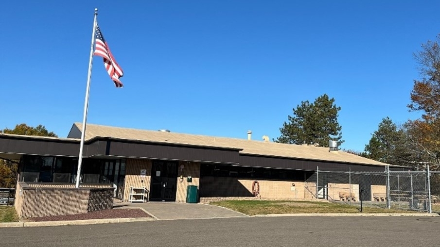 portrait of New York Animal Import Center with American flag on a flagpole near entrance against backdrop of a sunny sky