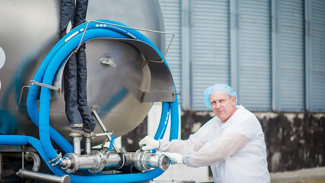 person in personal protective equipment standing in front of milk testing equipment