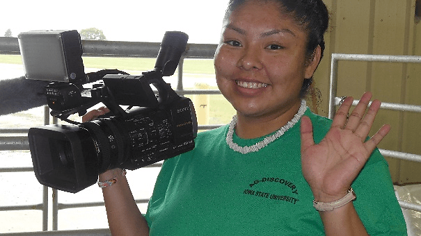 Female student holding a video camera and waving