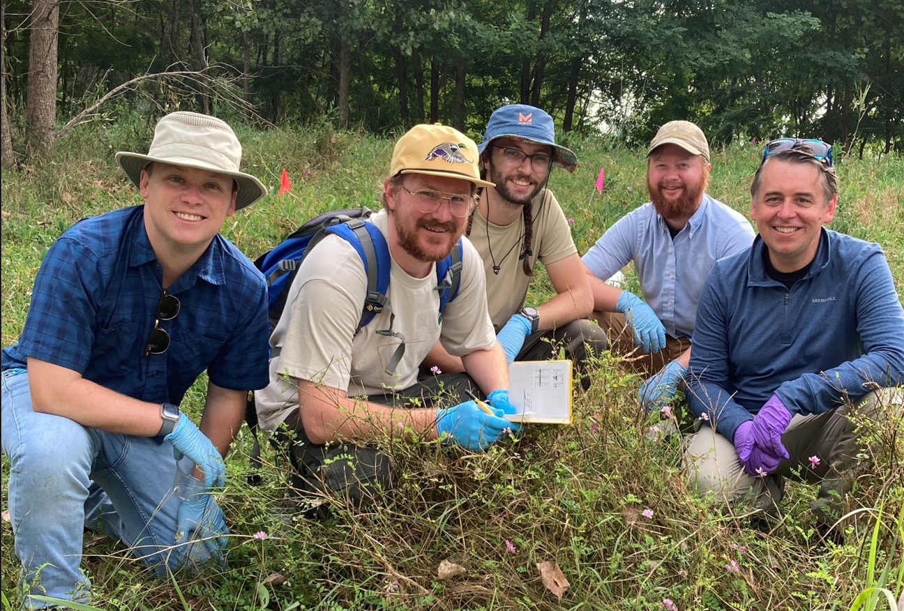 Five Federal Employees in field recording the number snails trapped.