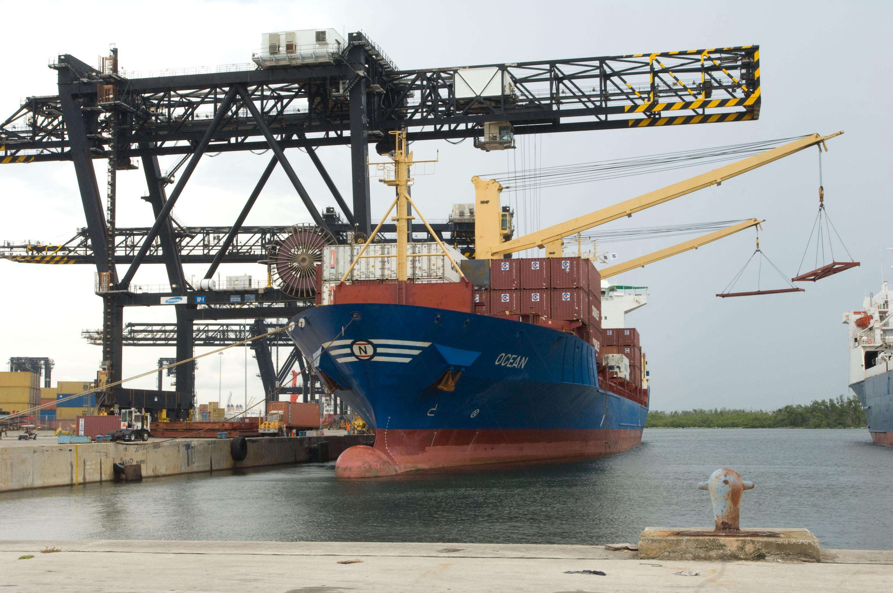 Blue cargo ship docked with cargo containers on deck