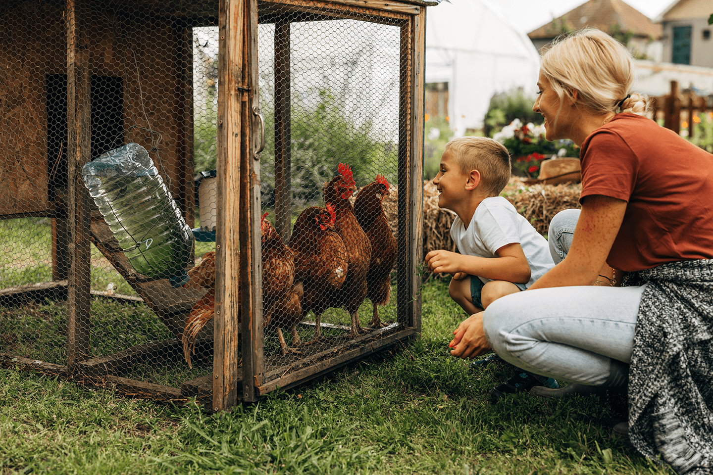 Mother and child looking at chickens in a coop
