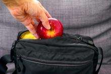 hand putting apple into a black bag